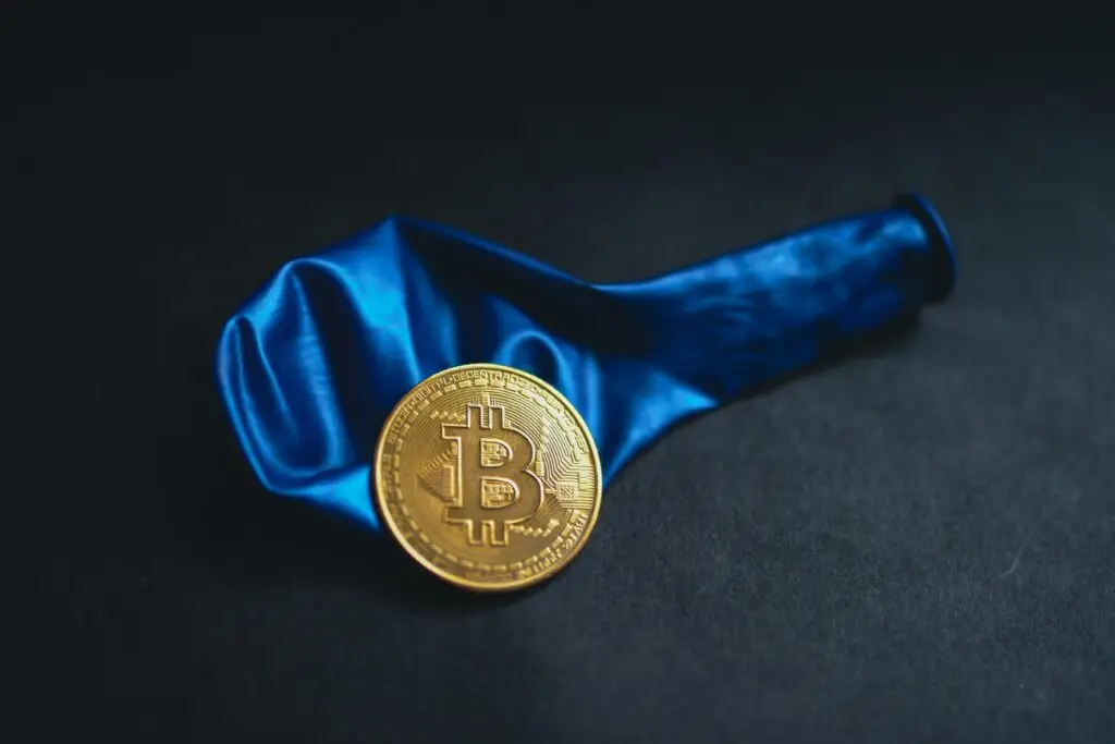 bitcoin laying on a blue deflated balloon